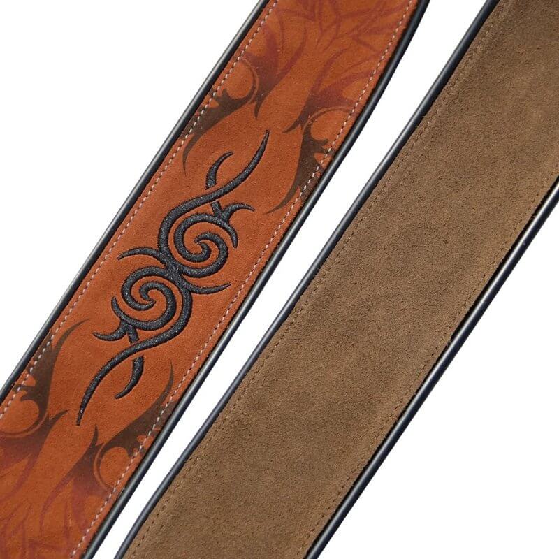 Details of a light brown suede guitar strap with a tribal pattern.