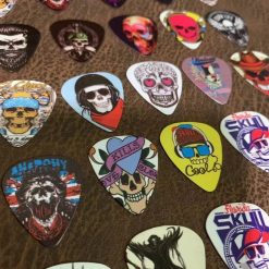 Detailed view of a set of 10 guitar picks with skull and death's head designs of 0.46mm thickness.