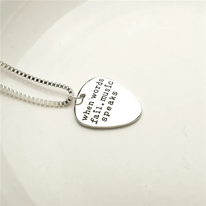 Detailed view of the pick-shaped medallion with the words "When words fail, music speaks".