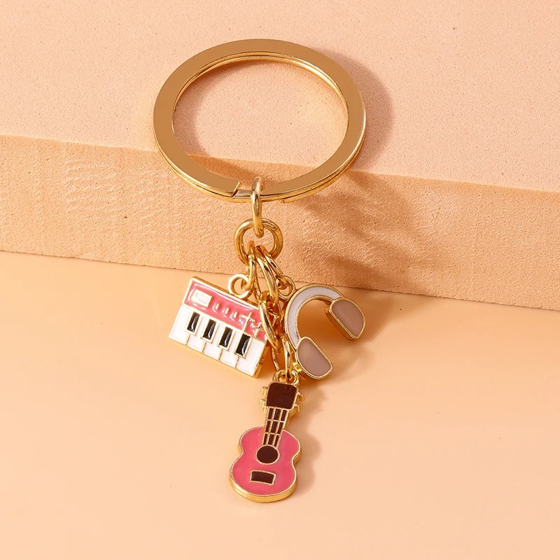 Metal keychain of a guitar and musical instruments in pink color