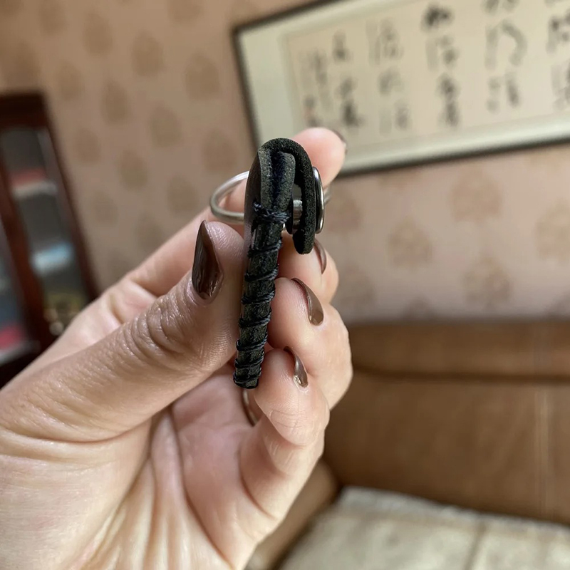 Side view of a guitar keychain made of genuine leather with a pick case.