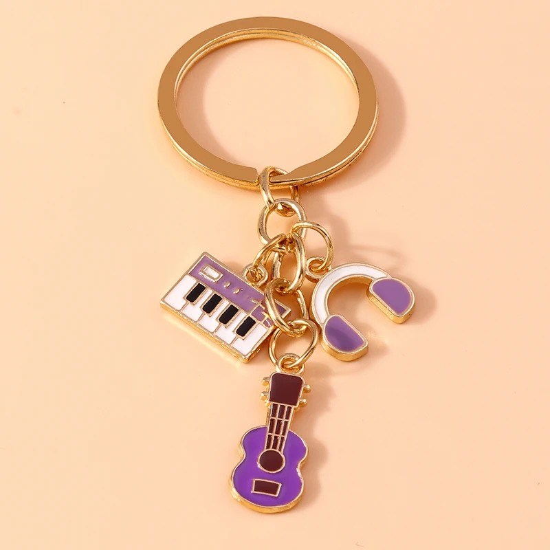 Metal keychain of a guitar and musical instruments in purple color