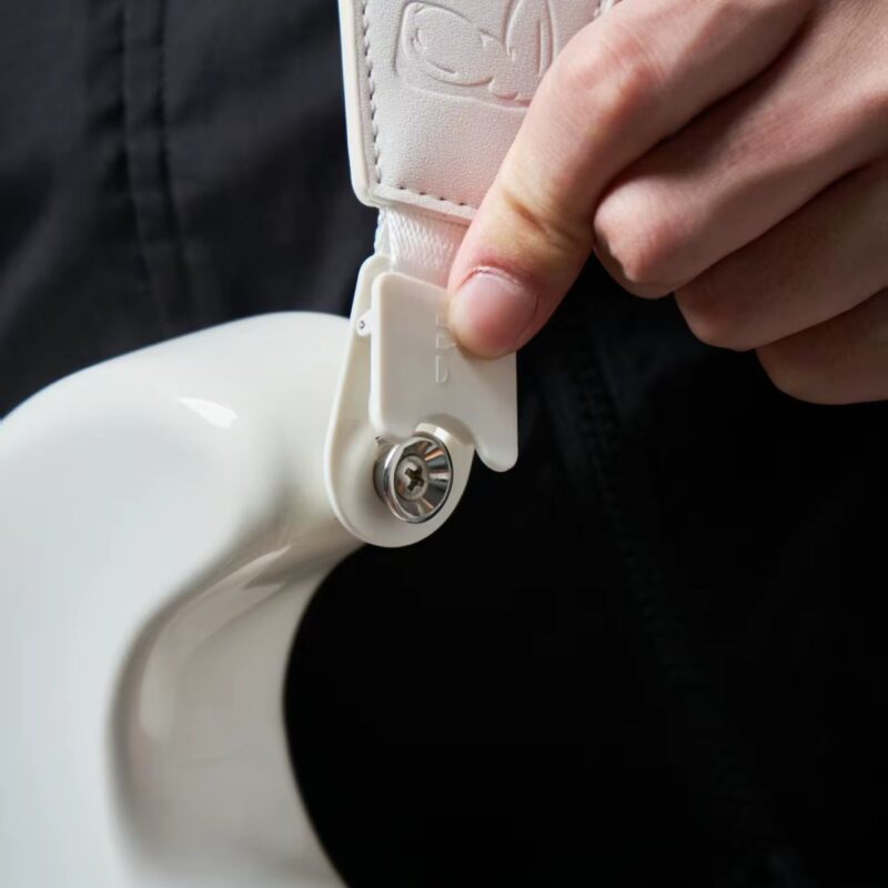 Main actionnant l'attache auto-lock à dégagement rapide de la sangle Power Grip sur le bouton de sangle d'une guitare électrique blanche